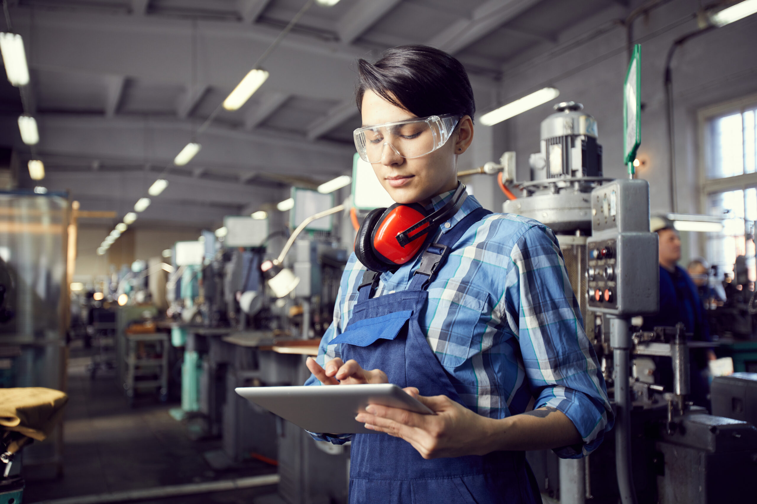 Busy factory woman adding information into tablet