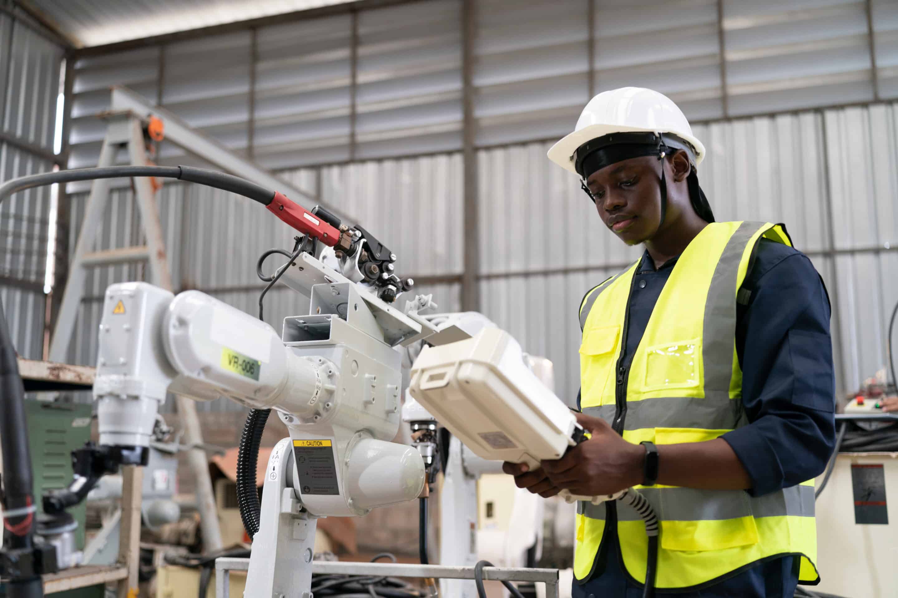 Industrial engineer using tablet for OPC UA monitoring and real-time OEE tracking with robotic equipment in manufacturing facility