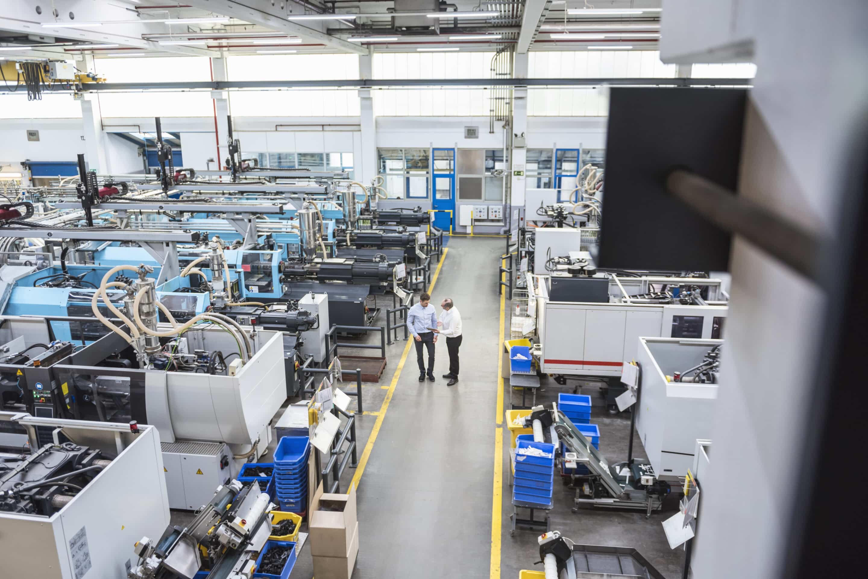 Manufacturing facility with real-time OEE monitoring - operators reviewing production line performance and equipment effectiveness