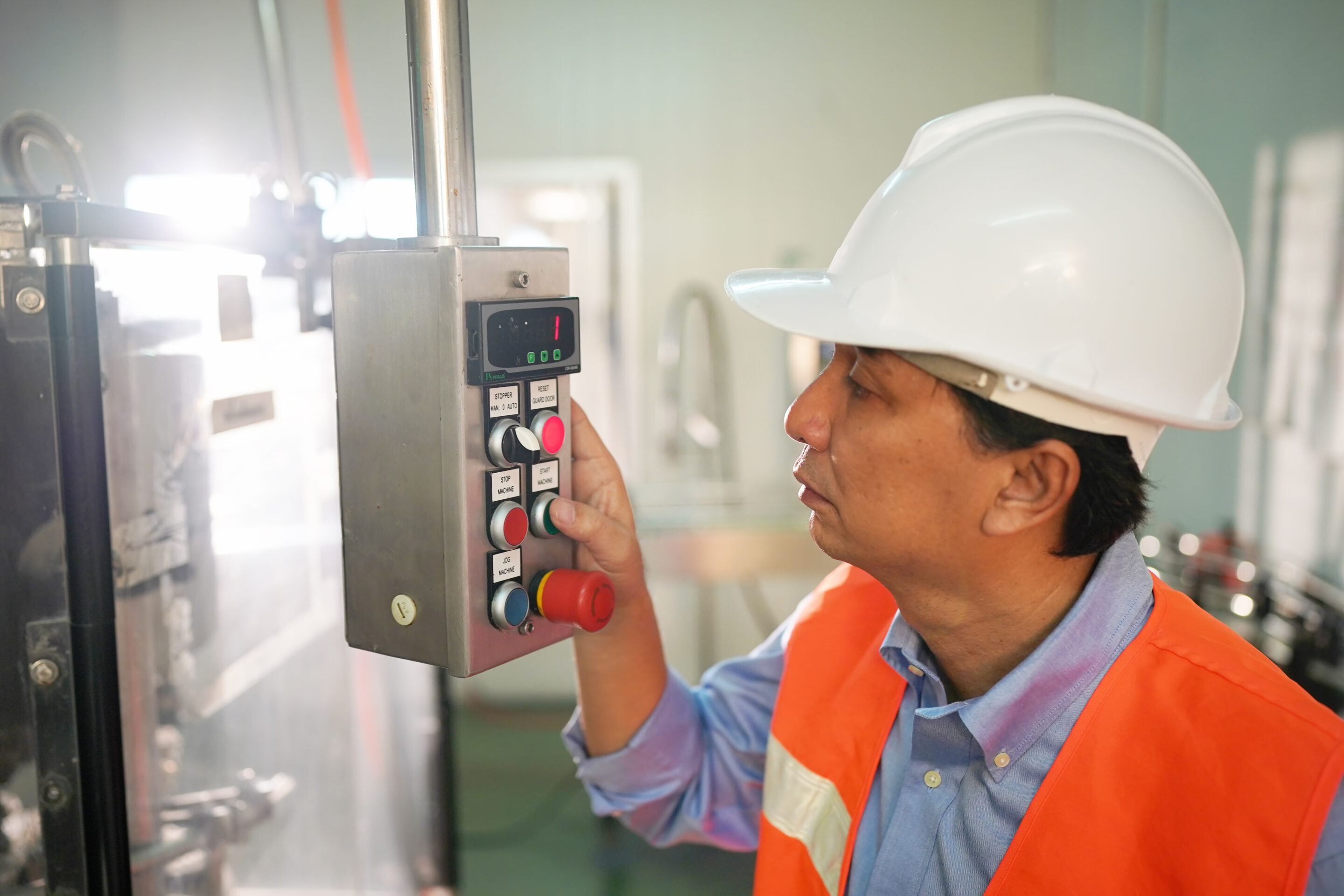 worker controlling the work of machine in production line at beverage industry.