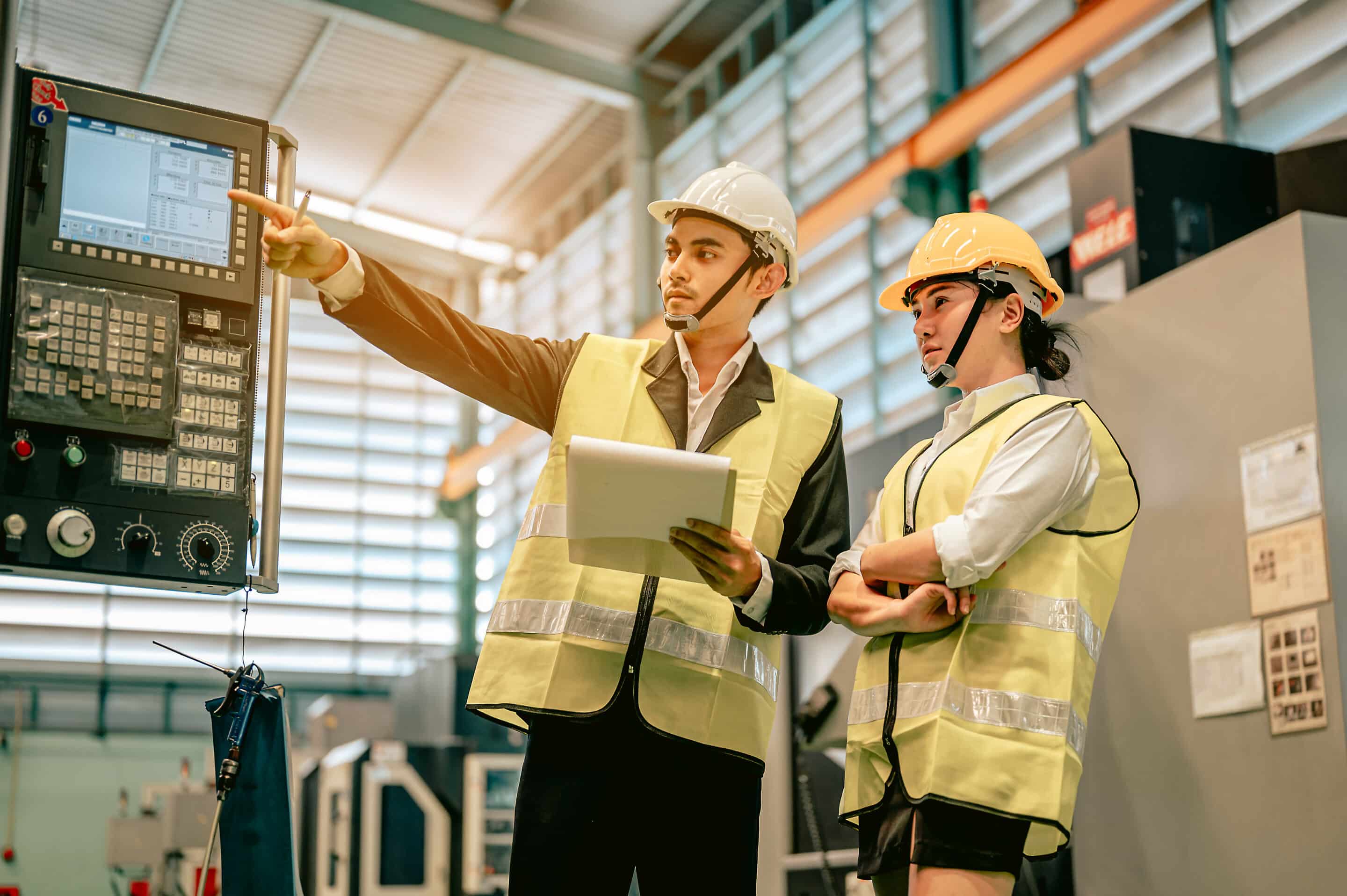 Two engineers reviewing TEEPTRAK vs Evocon OEE software on a factory control panel.